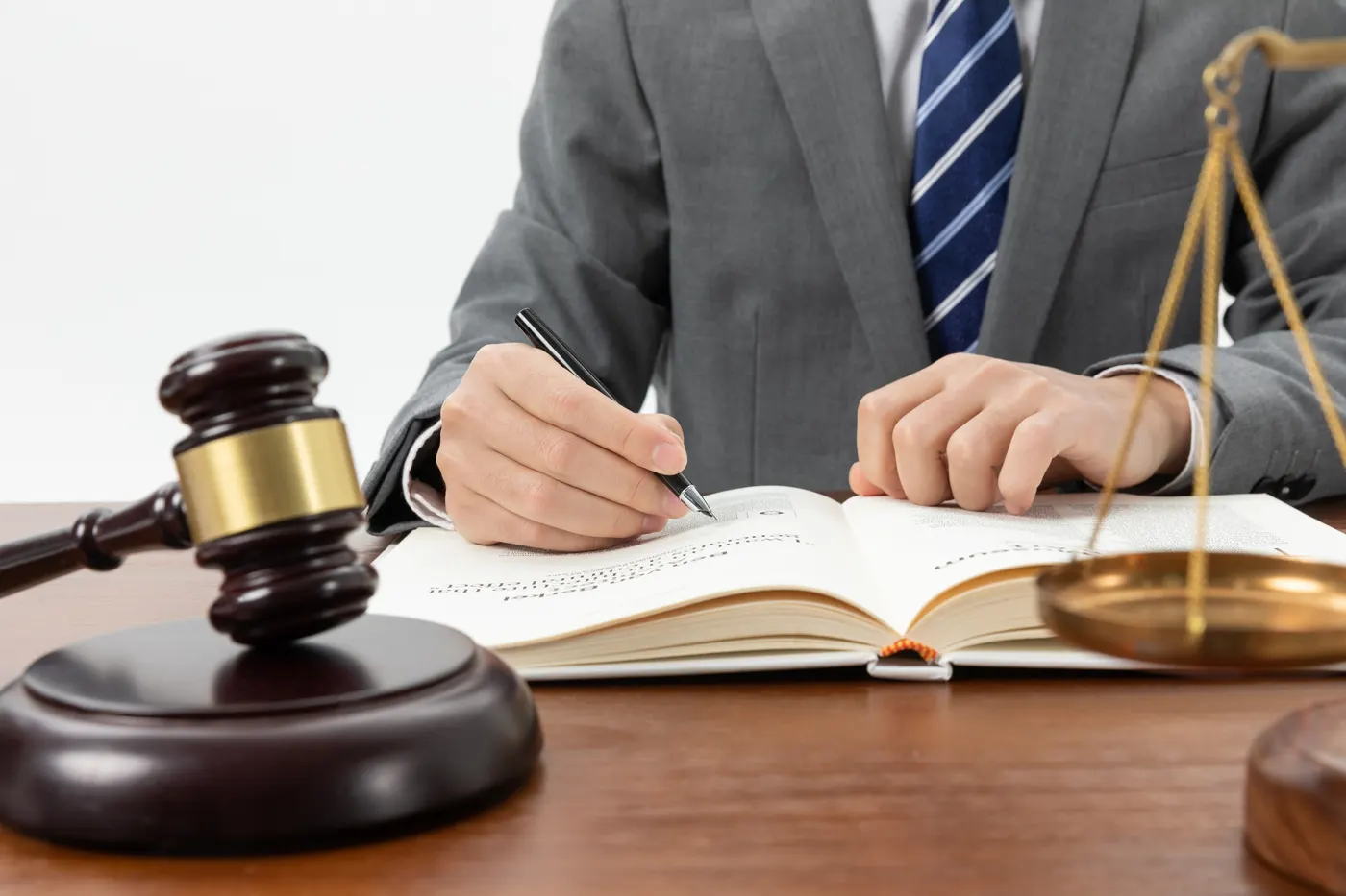 A lawyer taking notes in a book beside a gavel and the scales of justice